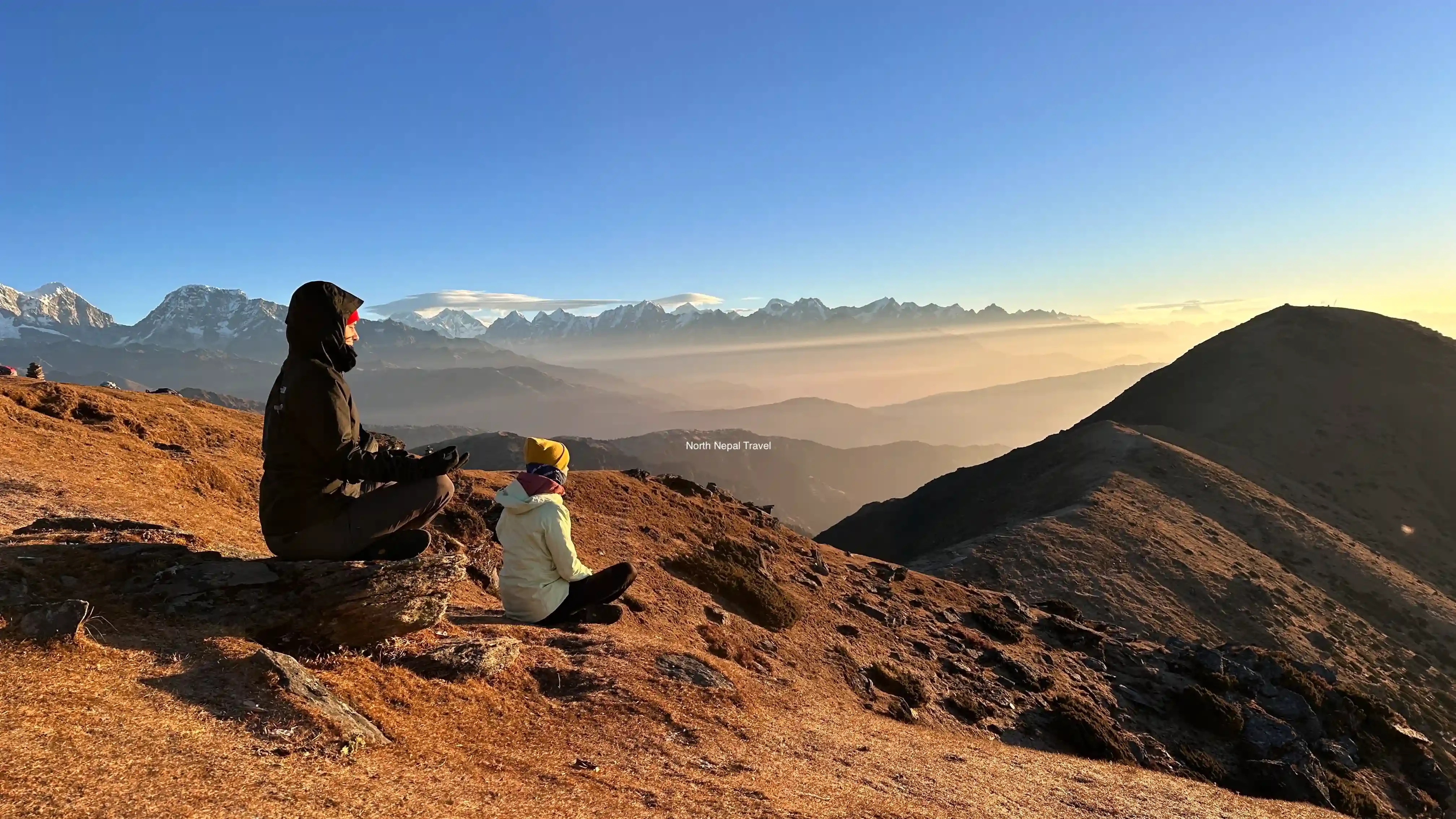 One male and one female trekker from North Nepal Trek meditating on Pikey Peak, with mountain background at the front during Pikey Peak Trek.